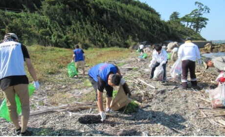 海岸でごみや流木を回収する清掃活動の様子の写真
