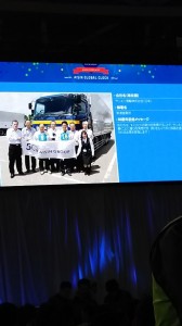 9:15スクリーンに映る当社新湊営業所（AISIN　GLOBAL CLOCKより）